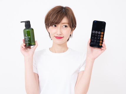 ハーバルリーフオーガニックシャンプーとiPhoneを持つ女性