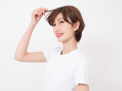 自分の髪をつまむ女性