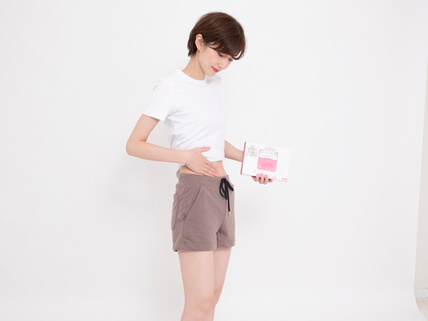 スルーラを飲んでスッキリしたお腹を触る女性