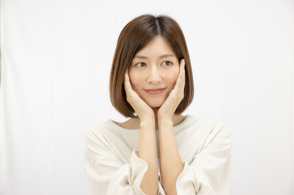 頬に手を当てて肌の潤いを実感する女性